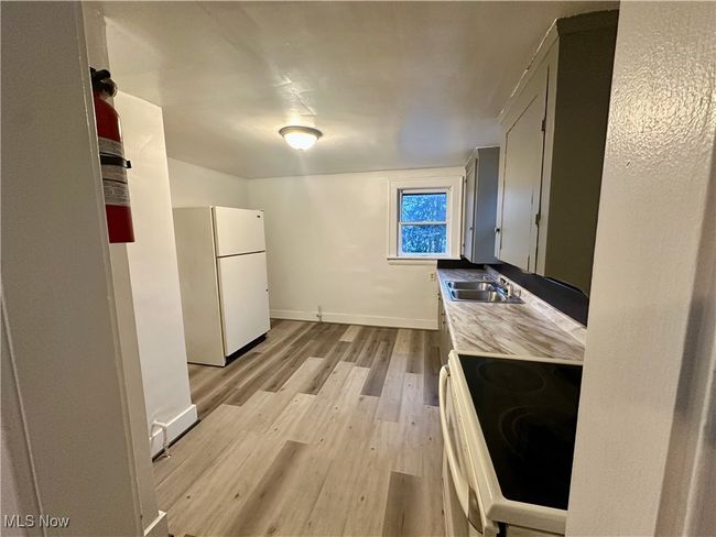 Kitchen with a sink, baseboards, light wood-style floors, white appliances, and light countertops | Image 13