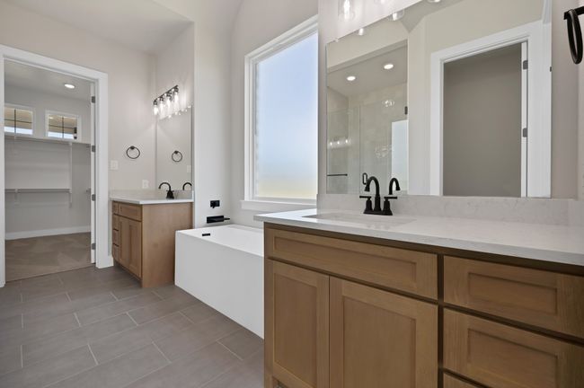 Bathroom featuring a shower stall, two vanities, a bath, and tile patterned flooring | Image 18
