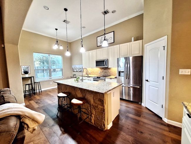Kitchen with stone island and breakfast bar, stainless steel appliances, built in microwave and farmhouse sink | Image 7