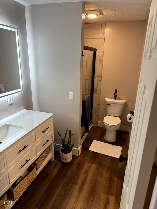 full bath featuring a stall shower, wood finished floors, toilet, and vanity | Image 27