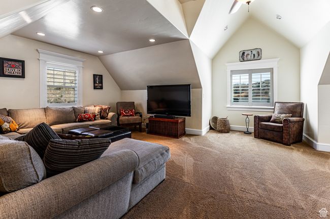 Carpeted living area featuring a wealth of natural light, vaulted ceiling, and baseboards | Image 22