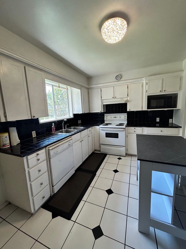 Kitchen featuring a sink, decorative backsplash, under cabinet range hood, and white appliances | Image 16