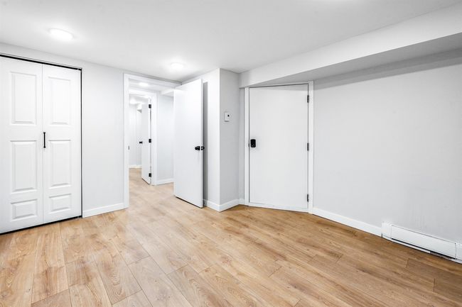 Unfurnished bedroom with multiple closets, light wood-style floors, baseboards, and a baseboard radiator | Image 8