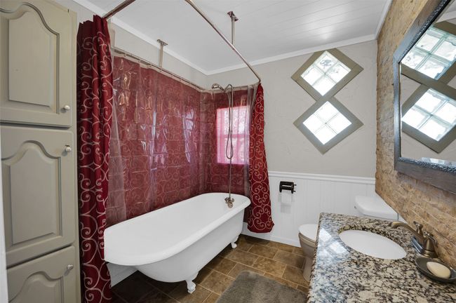 Bathroom with plenty of natural light, a wainscoted wall, a bathtub, toilet, and crown molding | Image 11