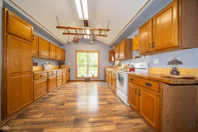 kitchen featuring white range with electric stovetop, wood finished floors, brown cabinets, and a sink | Image 18