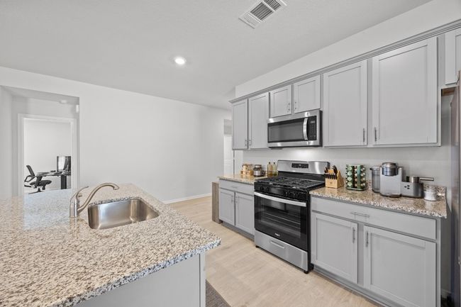 Kitchen featuring gray cabinets, a large sink, appliances with stainless steel finishes, and light wood finished floors | Image 9