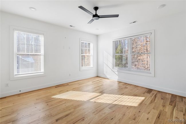 Light filled primary with hardwood floor and remote controlled ceiling fan. | Image 21