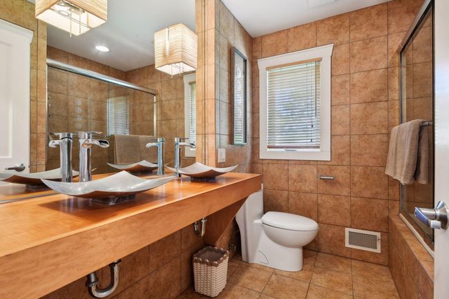Main level bath offers double vanity with vessel sinks, beautiful tile work on the floors and on tub/shower surround. Extra deep soaking tub! | Image 20
