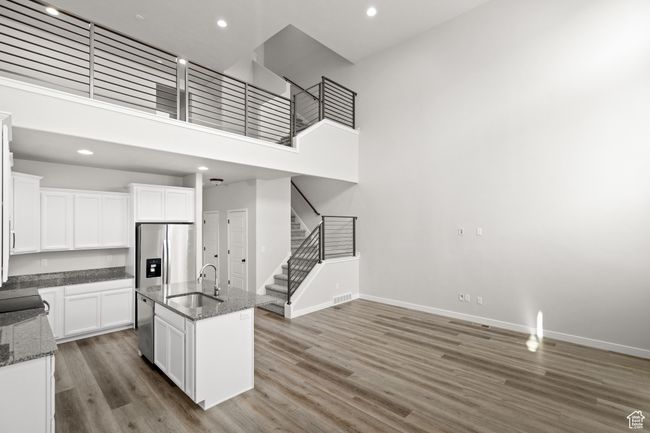 Kitchen featuring stainless steel appliances, wood finished floors, dark stone countertops, white cabinetry, and recessed lighting | Image 11