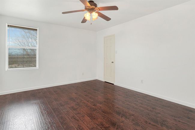 Unfurnished room featuring dark wood-style floors, baseboards, and ceiling fan | Image 31
