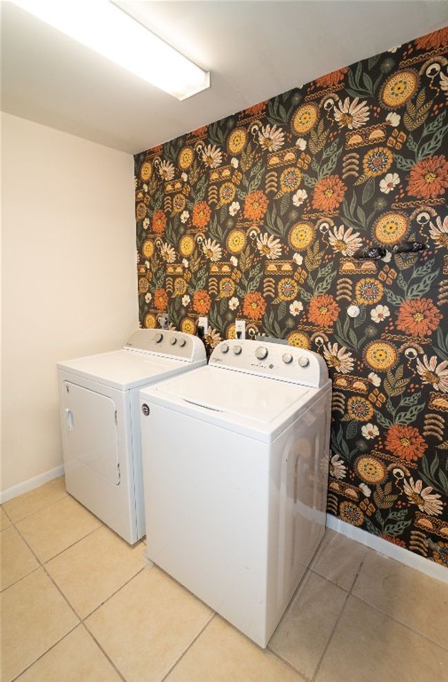 Laundry area featuring independent washer and dryer and light tile patterned flooring | Image 23