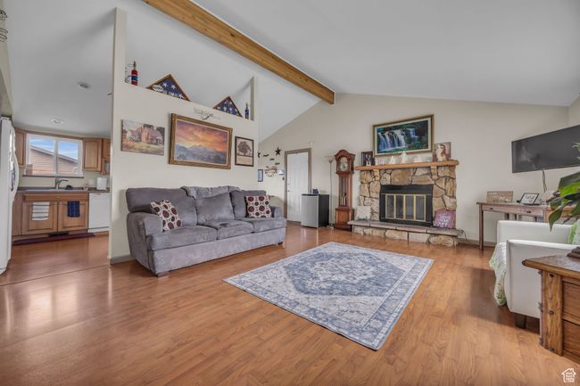 Living area featuring light wood-style flooring, high vaulted ceiling, beamed ceiling, and a fireplace | Image 4