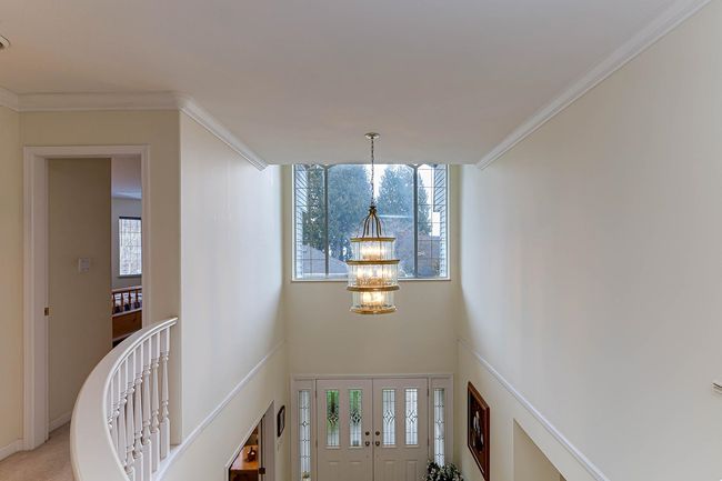 Foyer featuring a healthy amount of sunlight, a high ceiling, a chandelier, and crown molding | Image 24