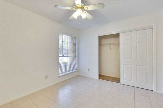 Unfurnished bedroom with light tile patterned flooring, a closet, and a ceiling fan | Image 21