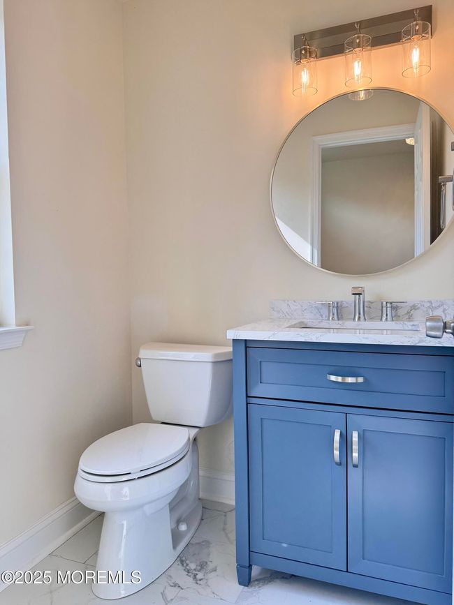 Half bath on main level with marble countertop and porcelain floor. | Image 10