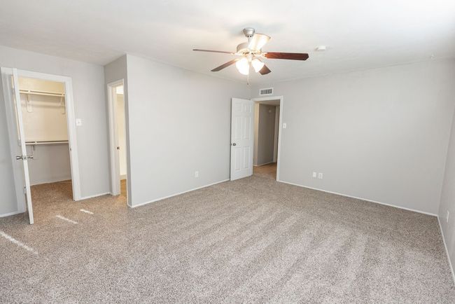Unfurnished bedroom with a walk in closet, carpet flooring, ceiling fan, visible vents, and a closet | Image 22