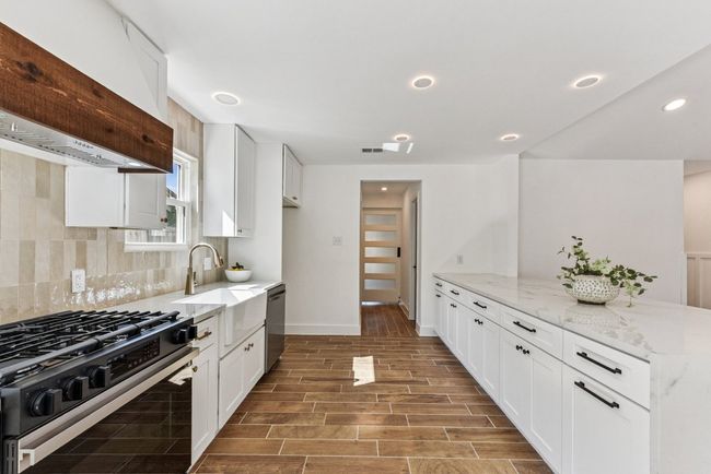 An entertainer’s dream kitchen with quartz countertops and sleek white cabinetry. | Image 4