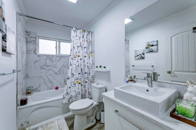 Bathroom featuring toilet, wood finished floors, shower / bathtub combination with curtain, vanity, and ornamental molding | Image 29
