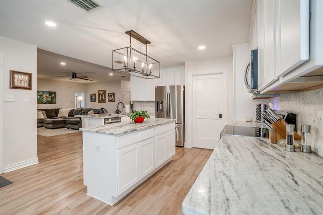 Kitchen featuring stainless steel appliances, open floor plan, a center island with sink, ceiling fan, and backsplash | Image 16