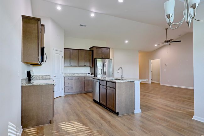 Kitchen featuring a ceiling fan, light wood-style flooring, a kitchen island with sink, appliances with stainless steel finishes, and lofted ceiling | Image 8