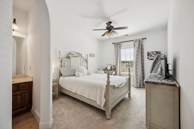 Bedroom with arched walkways, ceiling fan, and light carpet | Image 21