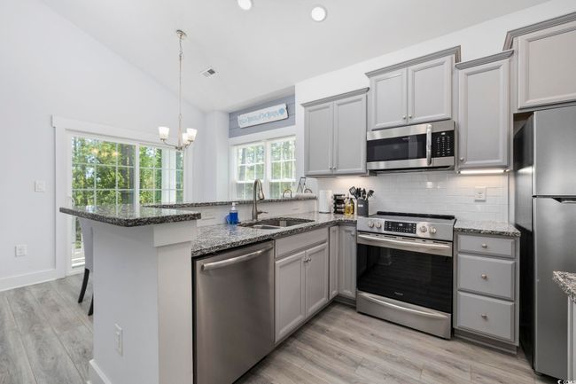 Kitchen with stainless steel appliances, a sink, decorative backsplash, gray cabinetry, and a peninsula | Image 13