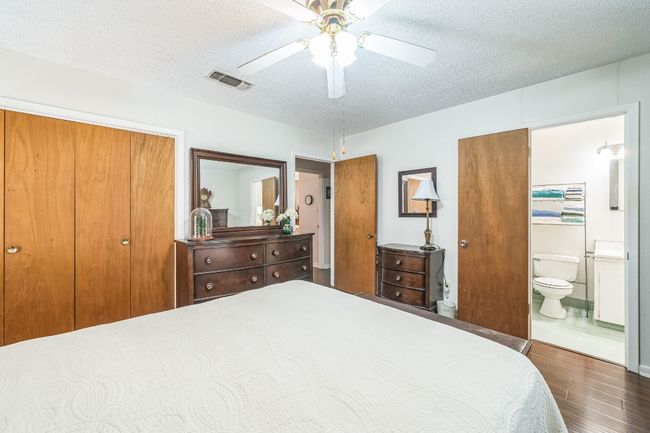 Bedroom with visible vents, a textured ceiling, connected bathroom, and wood finished floors | Image 18