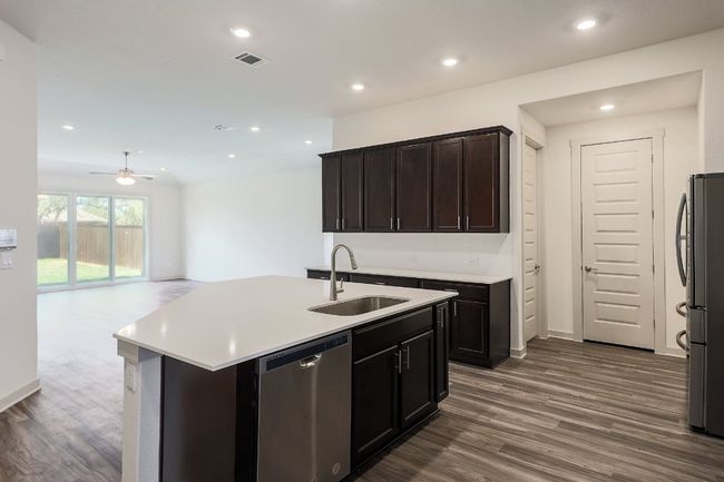 Living room is open to the kitchen featuring stainless steel appliances, light countertops, dark wood-style floors, a breakfast with sink and recessed lighting | Image 8
