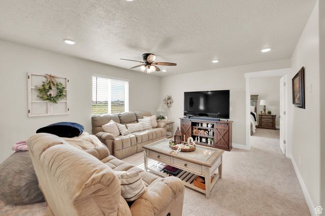 Living area with a ceiling fan, recessed lighting, light colored carpet, a textured ceiling, and baseboards | Image 20