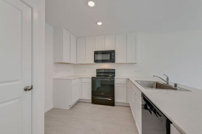 Kitchen with black appliances, white cabinets, recessed lighting, and light wood-style flooring | Image 10