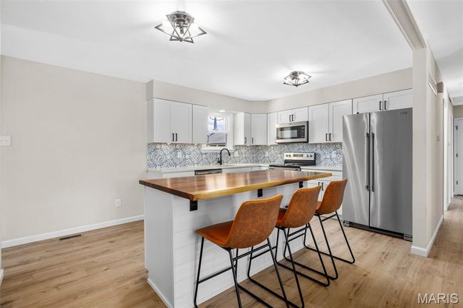Kitchen with appliances with stainless steel finishes, butcher block countertops, light wood-style floors, and backsplash | Image 12