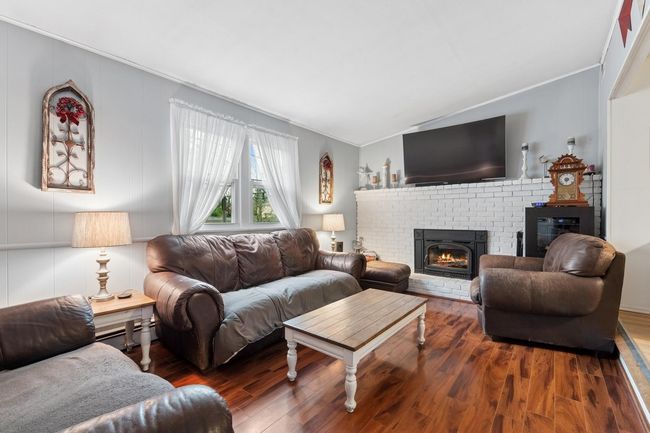 Den with a brick fireplace, ornamental molding, wood finished floors | Image 4