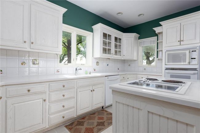 Kitchen with white cabinetry, white appliances, sink, light tile patterned floors, and backsplash | Image 41