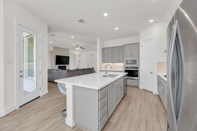 Kitchen featuring stainless steel appliances, gray cabinets, light countertops, visible vents, and a sink | Image 14