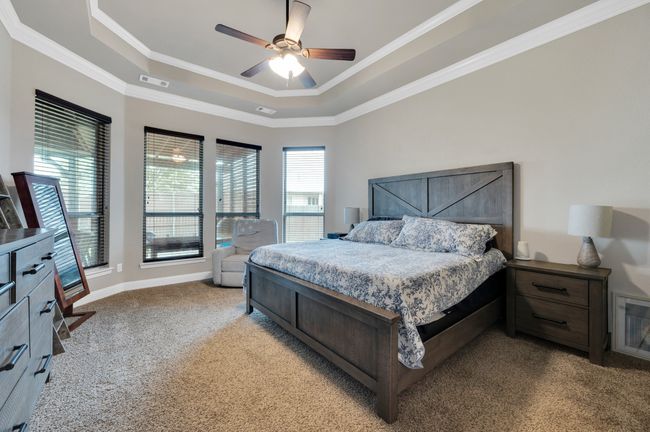 Bedroom with a raised ceiling, light colored carpet, ornamental molding, a ceiling fan, and baseboards | Image 18