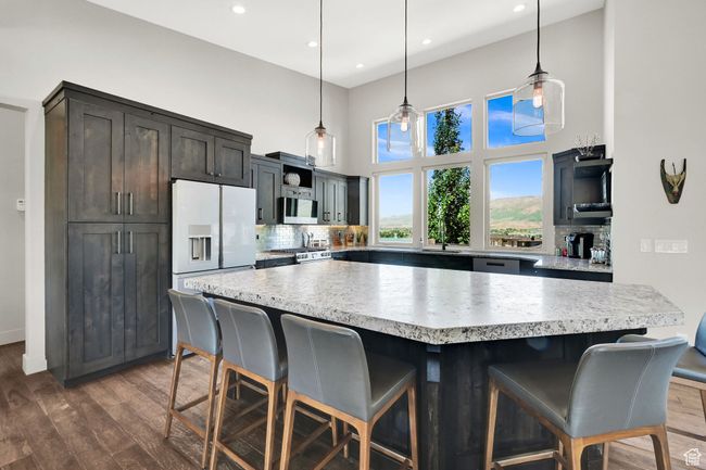 Kitchen with appliances with Platinum Glass finishes, tasteful backsplash, dark wood flooring, light countertops, and a high ceiling | Image 24