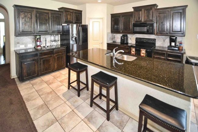 Kitchen with black appliances, a sink, a kitchen breakfast bar, and​​‌​​​​‌​​‌‌​‌‌​​​‌‌​​‌‌​‌​​​​​‌ backsplash | Image 4