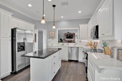 Kitchen featuring sink, white cabinetry, a center island, and stainless steel appliances | Image 3