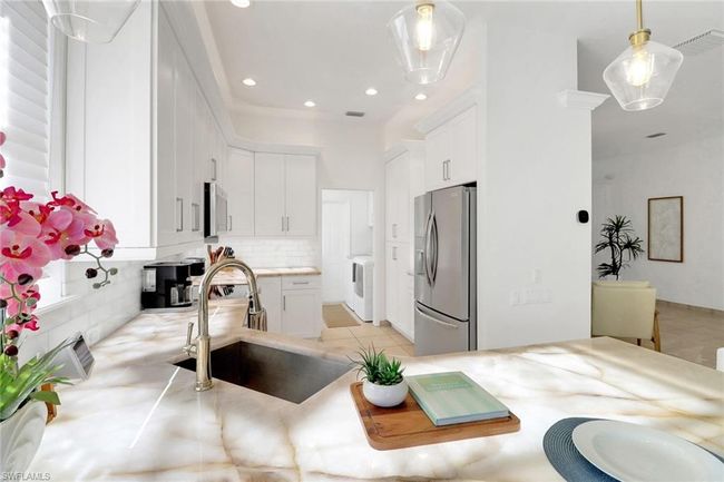 Kitchen with decorative backsplash, visible vents, appliances with stainless steel finishes, a sink, and white cabinetry | Image 9
