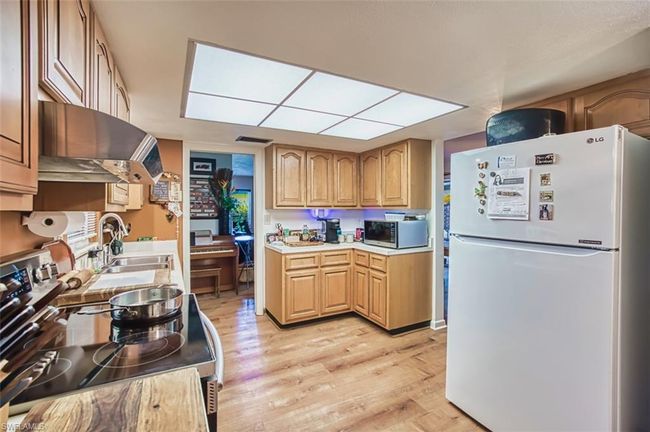 Kitchen with appliances with stainless steel finishes, extractor fan, light wood-style flooring, and light countertops | Image 17