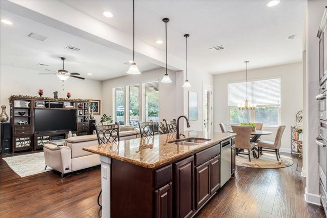 Kitchen with dark wood-type flooring, dark brown cabinetry, a chandelier, recessed lighting, and light stone countertops | Image 8