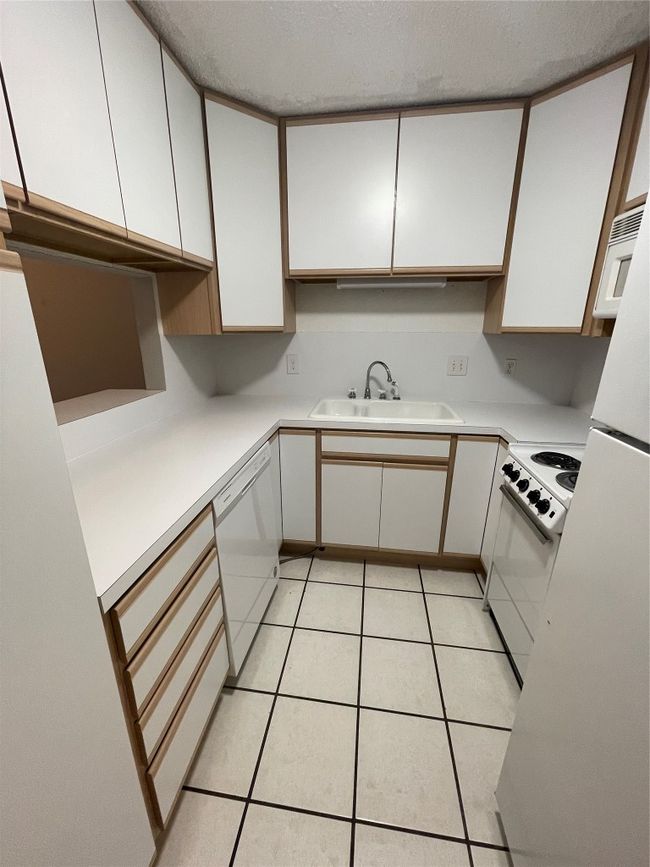 Kitchen with stove, dishwasher, white cabinets, light countertops, and a textured ceiling | Image 5