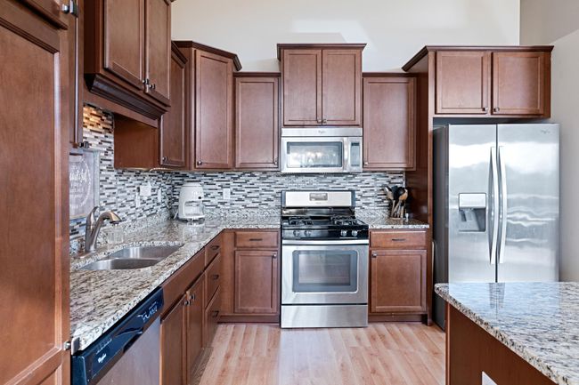 Spacious kitchen with large island, tons of cabinets and storage, stainless steel appliances, tile backsplash and granite counters. | Image 7