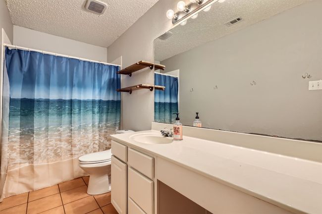 Bathroom with tile patterned flooring, vanity, toilet, and a textured ceiling | Image 24