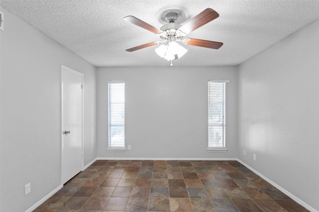 Spare room featuring baseboards, a ceiling fan, stone finish flooring, and a textured ceiling | Image 22