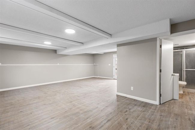 Finished below grade area featuring baseboards, wood finished floors, and a textured ceiling | Image 24