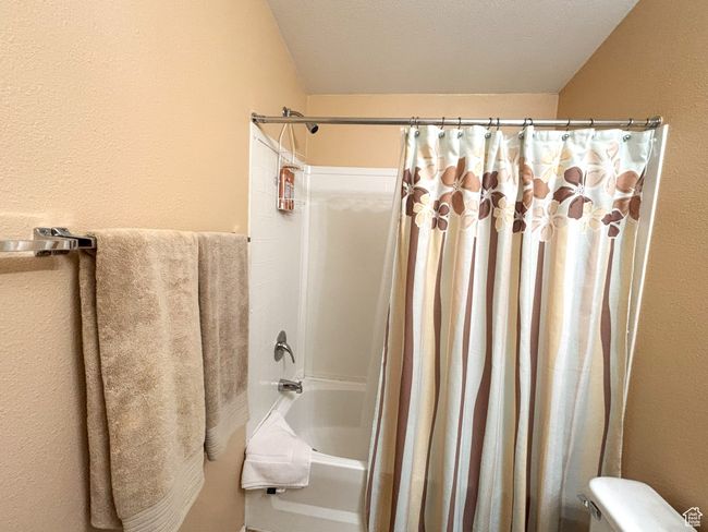 Full bath with shower / bath combo, toilet, and a textured wall | Image 33