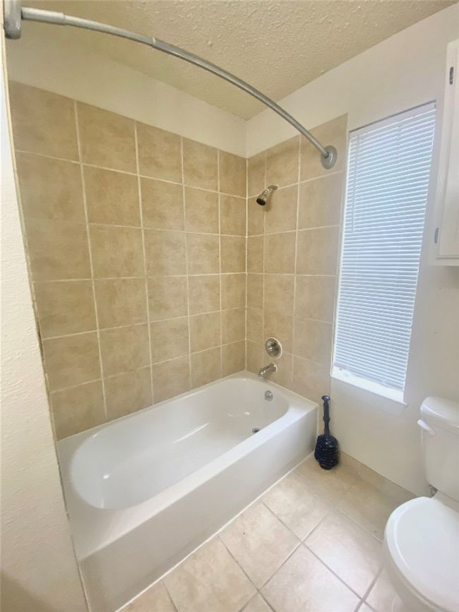 Full bath featuring tile patterned floors, a textured ceiling, toilet, and shower / tub combination | Image 23