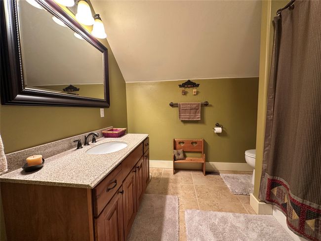 Full bathroom featuring lofted ceiling, vanity, curtained shower, and tile patterned flooring | Image 18