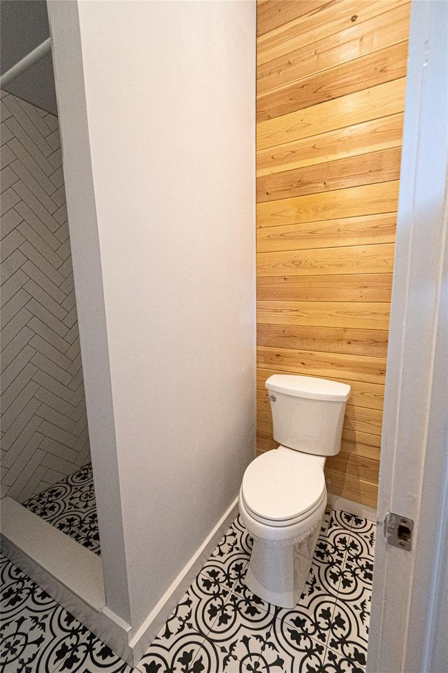 Bathroom with wood walls, a shower stall, and tile patterned floors | Image 16